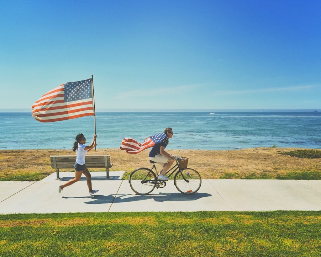 man riding bike and woman running holding flag of USA